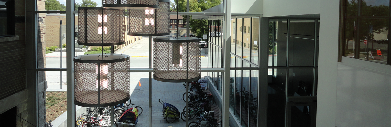 Bike racks seen through chandeliers and glass of Ames Pubic Library