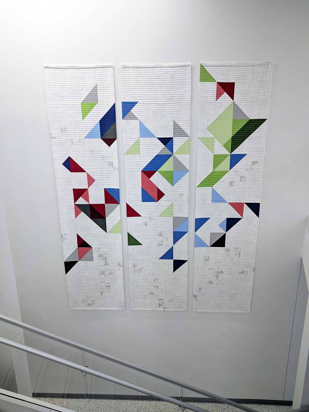 Quilt with geometric design hanging on wall